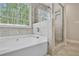 Bright bathroom featuring a soaking tub next to a glass-enclosed shower and large window at 12495 Concord Hall Dr, Alpharetta, GA 30005