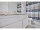 Bathroom showcasing a granite countertop, white cabinets, and a blue-striped shower curtain at 12495 Concord Hall Dr, Alpharetta, GA 30005