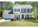 Charming two-story home boasts a manicured lawn, attached garage and a welcoming front porch with blooming flowers at 12495 Concord Hall Dr, Alpharetta, GA 30005