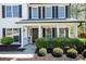 The front porch has a dark door, a nice wreath, and two beautiful hanging plants, surrounded by manicured shrubs at 12495 Concord Hall Dr, Alpharetta, GA 30005