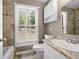 Bright bathroom with a window, tiled shower, and a toilet with cabinet storage at 3188 Sunnyford Ln, Lithonia, GA 30038