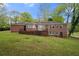 Spacious brick house with a lush green lawn, patio, and mature trees surrounding the property at 3188 Sunnyford Ln, Lithonia, GA 30038