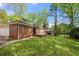 Charming brick home with a well-manicured lawn, mature trees, and a detached carport at 3188 Sunnyford Ln, Lithonia, GA 30038