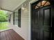 Charming entrance with a black door and a cozy porch, framed by lush greenery at 5711 Parks Rd, Cumming, GA 30041