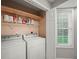 Bright laundry area with washer, dryer, storage shelving, and a window at 5711 Parks Rd, Cumming, GA 30041