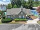 View of pool house and tennis court surrounded by lush greenery and manicured landscaping at 6815 Fairgreen Dr, Suwanee, GA 30024
