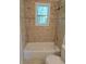 Clean bathroom featuring a bathtub with a window and tiled walls at 2065 Verbena St, Atlanta, GA 30314
