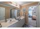 Well-lit bathroom includes double sinks, neutral decor, and a view into an adjacent bedroom at 115 Westbury Ln, Johns Creek, GA 30005