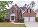 Charming two-story brick home boasts a well-manicured lawn and two-car garage at 115 Westbury Ln, Johns Creek, GA 30005