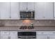 Kitchen stove and microwave with white cabinets, tile backsplash, and stainless steel appliances at 115 Westbury Ln, Johns Creek, GA 30005