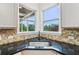 Kitchen with a dark countertop, stainless steel sink, tiled backsplash, and view from corner windows at 2539 Larson Creek Cove, Duluth, GA 30097
