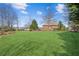 Expansive backyard featuring lush green grass, mature trees, and a charming two-story brick home at 5945 Boulder Bluff Dr, Cumming, GA 30040
