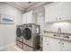 Laundry room features stainless steel washer and dryer, storage cabinets, and granite countertop at 5945 Boulder Bluff Dr, Cumming, GA 30040