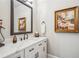 Elegant powder room with framed mirror, white marble countertop, stylish fixtures and a decorative painting at 5945 Boulder Bluff Dr, Cumming, GA 30040