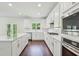 Well-lit kitchen featuring white cabinets, stainless steel appliances, and ample counter space for cooking at 5816 Creek Indian Dr, Sugar Hill, GA 30518