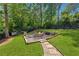 Landscaped backyard features a stone fire pit area, a pathway, and a wooded backdrop at 110 White Oak Trl, Cumming, GA 30028