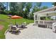 Stone patio with outdoor seating, fire pit, umbrella, and view of a lush green backyard at 110 White Oak Trl, Cumming, GA 30028