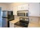 Efficient kitchen featuring stainless steel appliances, including a refrigerator, microwave, and electric stovetop at 475 Mount Vernon Ne Hwy # C-220, Sandy Springs, GA 30328