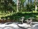 Concrete patio featuring two chairs and bordered by lush greenery, offering a tranquil outdoor space at 1234 W Wylie Bridge Rd, Woodstock, GA 30188