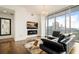 Bright living room with a modern fireplace, cityscape view, hardwood flooring, and luxurious black sectional at 1065 Peachtree Ne St # 2803, Atlanta, GA 30309
