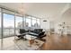 Bright living room with floor-to-ceiling windows, city views, modern decor, and a luxurious black sectional sofa at 1065 Peachtree Ne St # 2803, Atlanta, GA 30309