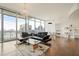 Bright living room with floor-to-ceiling windows, modern chandelier, and sleek black leather sofa at 1065 Peachtree Ne St # 2803, Atlanta, GA 30309