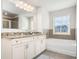 Bright bathroom with a granite countertop vanity, tub, and gray tile accent at 4568 Mantova Dr, Buford, GA 30519