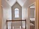 Upstairs hallway featuring an arched window, wood railing and trim, and views of bedrooms at 128 Brookhaven Ln, Mcdonough, GA 30253