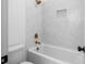 White tub and shower with white herringbone tile and gold fixtures at 461 Maypop Ln, Woodstock, GA 30188