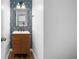 Chic powder room with wood-look vanity, modern mirror, and geometric wallpaper accent wall at 3377 Park Pointe Cir, Scottdale, GA 30079