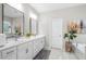 Bright bathroom featuring double sinks with white cabinets, soaking tub, and tiled floors at 3377 Park Pointe Cir, Scottdale, GA 30079