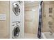 Tiled bathroom featuring stacked washer/dryer, accessible tub/shower combo with grab bars at 2637 Peachtree Ne Rd # 407, Atlanta, GA 30305