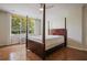 Bedroom with wood floors, four-poster bed frame, and a window overlooking lush greenery at 2637 Peachtree Ne Rd # 407, Atlanta, GA 30305
