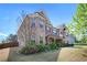A beautiful two-story brick home, showcasing its well-maintained lawn and colorful flower beds under a bright blue sky at 6150 Birchfield Trl, Cumming, GA 30041