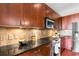 Well-equipped kitchen features dark wood cabinetry, stone backsplash, granite counters, and modern stainless steel appliances at 711 Cosmopolitan Ne Dr # 347, Atlanta, GA 30324