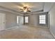 Spacious main bedroom featuring tray ceiling, ceiling fan, neutral carpet and access to the bathroom at 90 Ashford Dr, Oxford, GA 30054