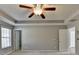 Primary bedroom with fan, tray ceilings, neutral carpet and view to Primary bathroom and walk in closet at 90 Ashford Dr, Oxford, GA 30054