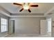 Bedroom view with fan, tray ceiling, neutral carpet, access to Primary bathroom and walk in closet at 90 Ashford Dr, Oxford, GA 30054