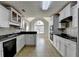 Galley kitchen with white cabinets, tiled backsplash, black appliances, and tiled floors at 90 Ashford Dr, Oxford, GA 30054