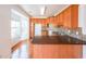 Kitchen featuring wood cabinets, dark countertops, a breakfast bar, and hardwood floors at 1294 Park Pass Way, Suwanee, GA 30024