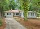 Single-story home featuring a sunroom, and a driveway in a lush, wooded setting at 3452 Ridgecrest Dr, Powder Springs, GA 30127