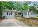 Charming home with light-colored siding, a metal roof, and a sunroom addition, all nestled among mature trees at 3452 Ridgecrest Dr, Powder Springs, GA 30127