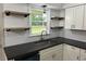 Well-designed kitchen featuring black countertops, white cabinets, and floating shelves at 3452 Ridgecrest Dr, Powder Springs, GA 30127