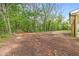 Dirt yard with surrounding forest and the side of a house with a porch at 5224 W Mountain St, Stone Mountain, GA 30083
