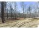A sloping backyard with tall trees, newly planted grass and an empty firepit area at 5567 Tyree Rd, Winston, GA 30187