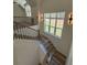 Well-lit staircase with wood and black iron railings, wood steps and views of the trees from the landing at 5567 Tyree Rd, Winston, GA 30187