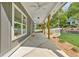 View of a covered patio featuring gray siding, wooden columns, concrete floor, ceiling fans, and manicured landscaping at 5232 W Mountain St, Stone Mountain, GA 30083