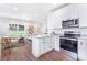 Bright open concept kitchen with white cabinets, stainless steel appliances, and an island overlooking the living area at 5232 W Mountain St, Stone Mountain, GA 30083