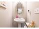 Stylish powder room featuring a pedestal sink, elegant mirror, and modern fixtures at 7144 Gladstone Cir, Stonecrest, GA 30038