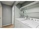 Well-lit laundry room featuring a white washer and dryer and storage shelving above at 2529 Ridgecrest Nw Dr, Kennesaw, GA 30152